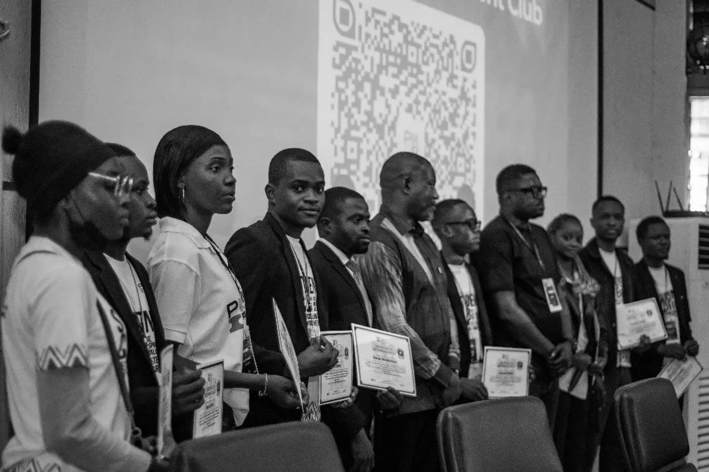 Une douzaine de participants alignés devant un écran, chacun tenant son certificat, à l'issue d'une session du club étudiant.